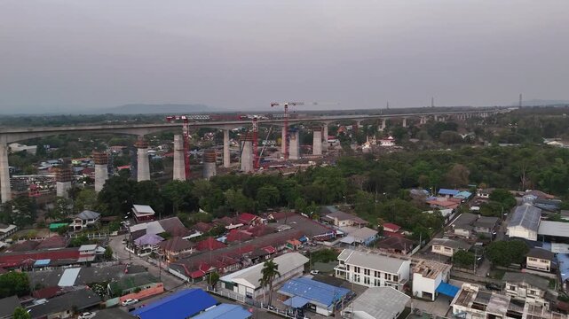 Aerial approach of Thailand high-speed train bridge during construction surrounded by rural villages and farmland in Pak Chong.