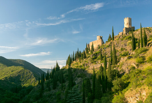 Medieval stone ruins perched on a rocky hillside with cypress trees represent a popular tourism destination for history and travel, Four Lastours castles, Languedoc-Roussillon, France.