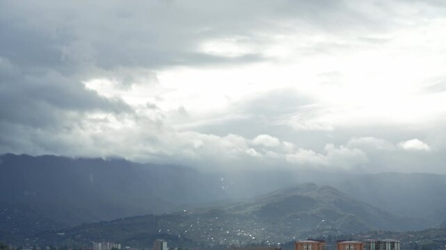 Panning timelapse moving thunderclouds before storm, view of the city near mountains. Sunrays break through the clouds. Stormy weather, melancholy, depression