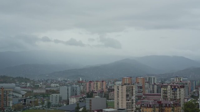 Panning time lapse city view near mountain, cars driving along streets, moving thunderclouds before storm. Batumi pan city life. Adjara, Batumi timelapse Georgia