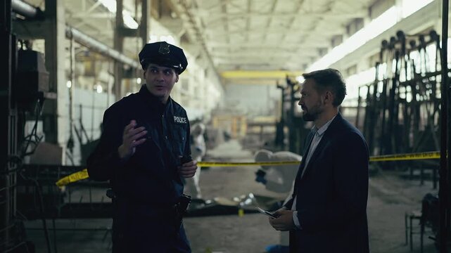 Middle-aged detective and police officer discussing murder case at crime scene