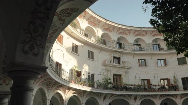 Handheld footage of Plaza del Cabildo in the historic center of Seville, Spain. Elegant Andalusian architecture, arches and traditional Mediterranean atmosphere in warm sunlight.