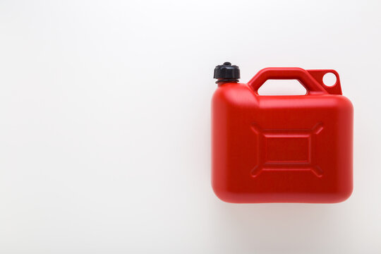 New red plastic 5L canister for car petrol on light gray table background. Closeup. Empty place for text. Flat lay. Top down view.