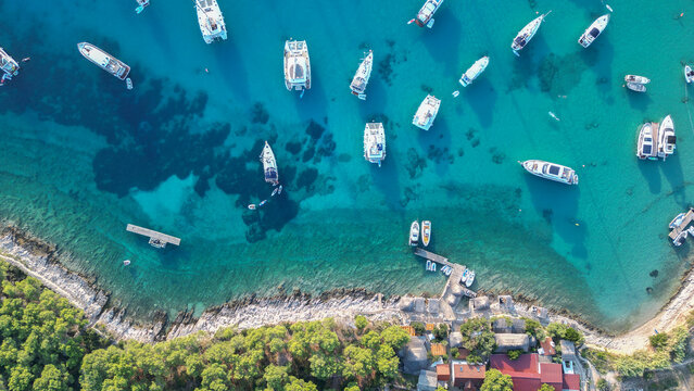 Hvar, Croatia - 21 August 2023: Aerial view of Vinogradisce bay with numerous yachts anchored in turquoise waters along the rocky coastline and lush pine trees.