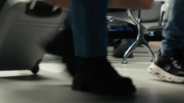 Close up of tourist carrying trolley in airport lounge, going to boarding gate for checkin. Traveler pushing wheeled luggage in aviation terminal, walking, doing journey back home, camera A