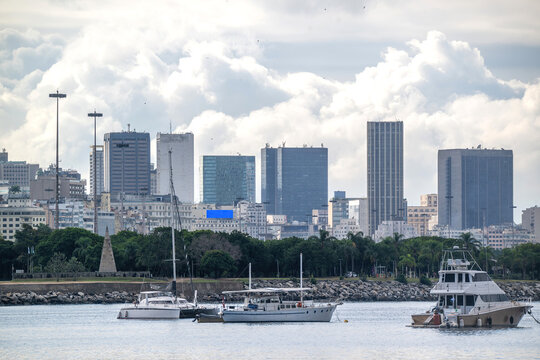 View of boats moored in the harbor with the modern skyline of the Centro district under a cloudy sky in Rio de Janeiro, State of Rio de Janeiro, Brazil.