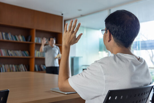 Motivated asian man in casual clothes greeting his colleague in a bright coworking space on a productive morning, ready to collaborate for work success