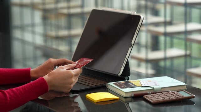 Woman holding credit cards while making a successful online payment on laptop computer, representing e-commerce, digital banking, and secure online shopping at home.