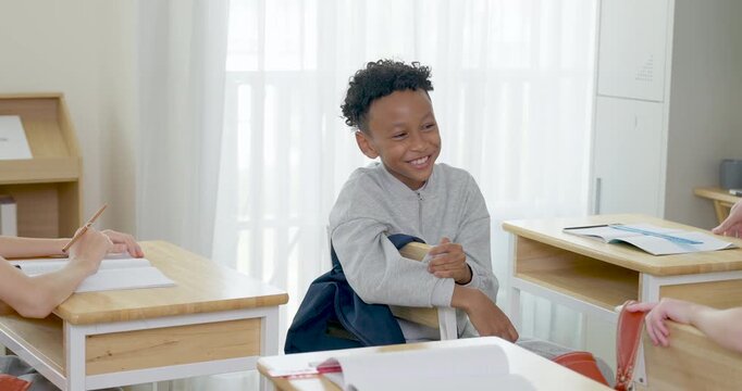 Elementary boy smiles and listens while female classmate talks nearby during back to school classroom activity, friendly peer interaction builds confidence, communication, participation, belonging