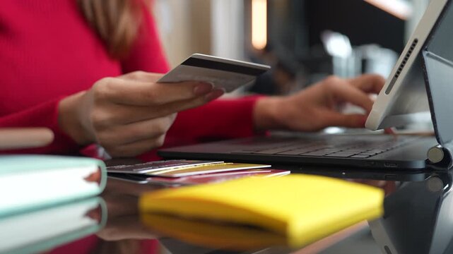 Woman holding credit cards while making a successful online payment on laptop computer, representing e-commerce, digital banking, and secure online shopping at home.