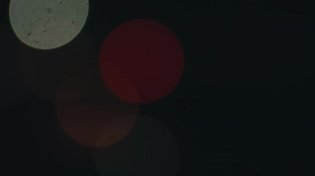 Beautiful blurry city traffic lights creating a vibrant and abstract bokeh effect, with colorful orbs moving gracefully against a dark, atmospheric backdrop perfect for urban night scenes