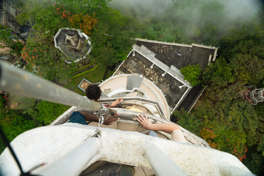 View of people climbing the narrow spiral staircase of Ambuluwawa Tower overlooking lush green forests and misty mountains in Gampola, Central Province, Sri Lanka.