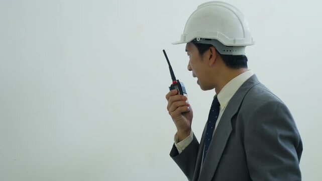 Man hard hat walkie talkie construction worker engineer suit helmet inspecting white wall with wireless meter plain office space side view communication scene calm focus construction site safety work