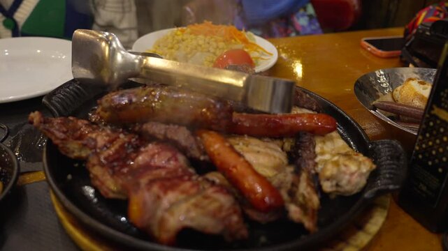 Close up of sizzling mixed grilled meat platter with sausages, pork, and beef served in a traditional restaurant in Madrid, Spain.
