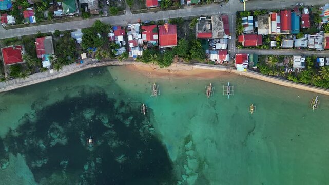 Picturesque aerial top-down view of Magnesia Del Norte in Virac, Catanduanes with shoreline homes, bangka boats, and clear coastal water