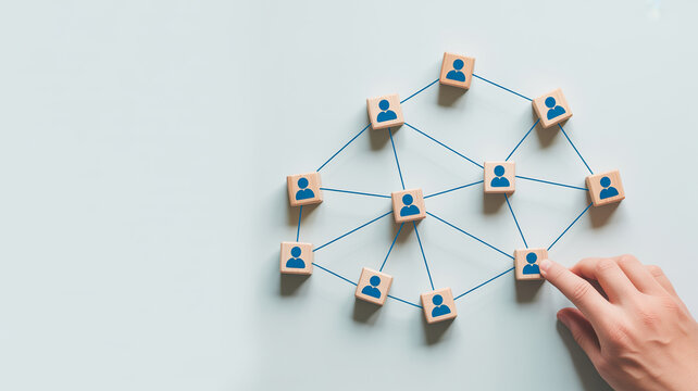 A network of wooden blocks featuring person icons is connected by lines, with a finger interacting with one block on the edge of the network.