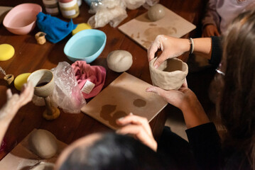 Obraz premium Woman hands shaping clay pottery on wooden table high angle view of female artisan working in craft studio