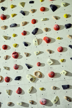 Vertical shot of indoor climbing wall displaying colorful handholds and footholds, supporting fitness training and recreation concepts