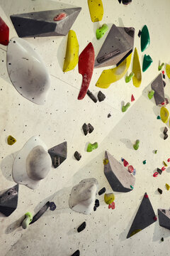 Vertical shot of indoor climbing wall featuring colorful holds and training volumes, supporting fitness practice and sport challenge