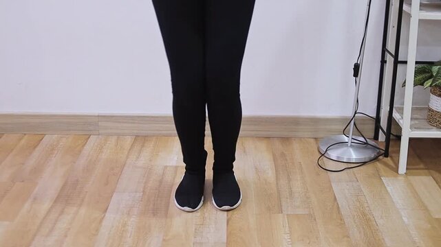 Low angle view of person in leggings and sneakers performing footwork and dance on wooden floor