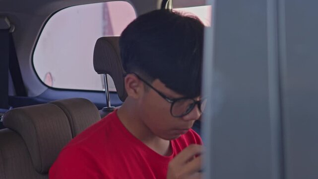 Young siblings sitting concentrating on intense mobile gaming while traveling together in car