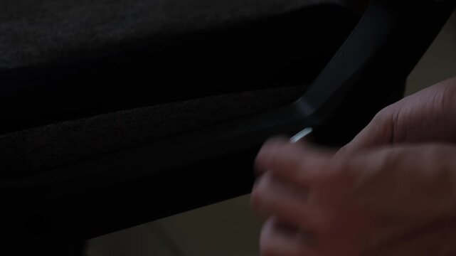 Close-up shot of hands using an allen wrench to adjust a gaming chair component during indoor furniture assembly