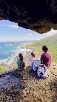 Mom and daughters relax at vista overlooking scenic Robberg coastline. Vertical