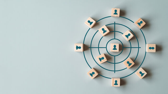 Wooden blocks with person icons arranged in concentric circles on a target, representing a focused recruitment or marketing strategy.