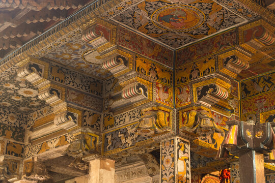 View of the ornate hand-painted wooden ceiling and carved pillars featuring traditional Kandyan motifs and animal figures in Kandy, Central Province, Sri Lanka.