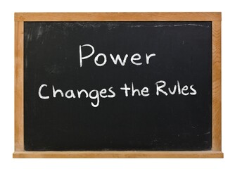 Fototapeta premium Power changes the rules written in white chalk on a black chalkboard isolated in a wooden frame on white