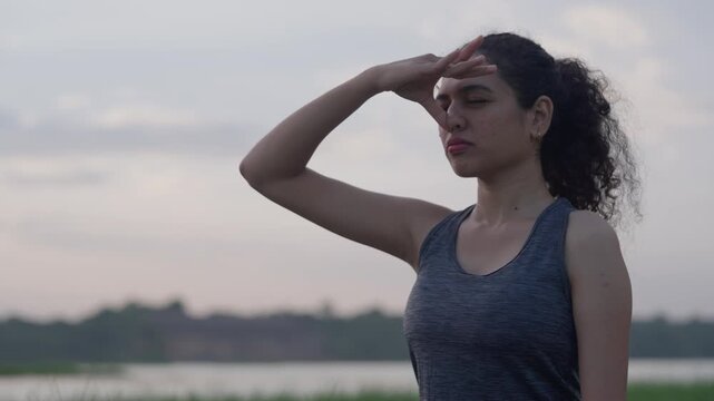 A slow-motion of a South Asian Woman in backbend doing yoga by a calm lake at twilight