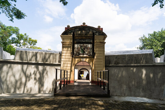 View of the historic entrance to the Star Fort featuring a stone archway with a coat of arms and a wooden bridge under a bright sky in Matara, Southern Province, Sri Lanka.