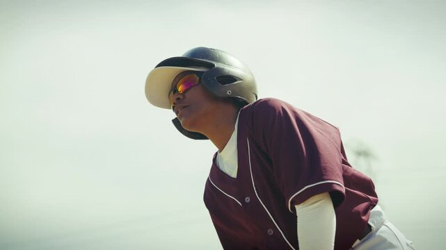 Focused baseball player in a batting helmet and uniform stands ready, awaiting the next play on the diamond. Determination is clear.