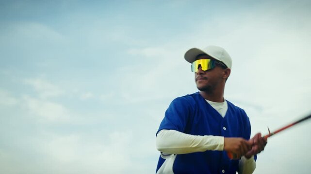 Young male baseball player in a blue jersey and cap practices his batting swing. He prepares for the game, focusing on technique and form.