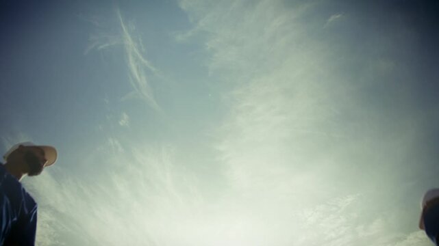 Baseball team huddles, then throws a baseball high. Represents unity, strategy, and athletic play under a vast sky.