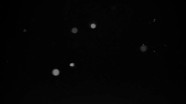 Floating Soft Dust Particles Ambient Light Bokeh Blur - Minimalist Slow Motion Glitter Specks on Black Background - Cinematic Magical Glow Backlight Atmosphere Overlay