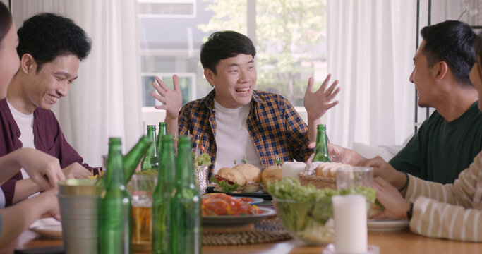 Happy hour good warm summer time diner indoor home. Group of asia people young adult friend man and woman sit at dining table joy fun talk or eat food and drink beer alcohol bottle glass inside house.