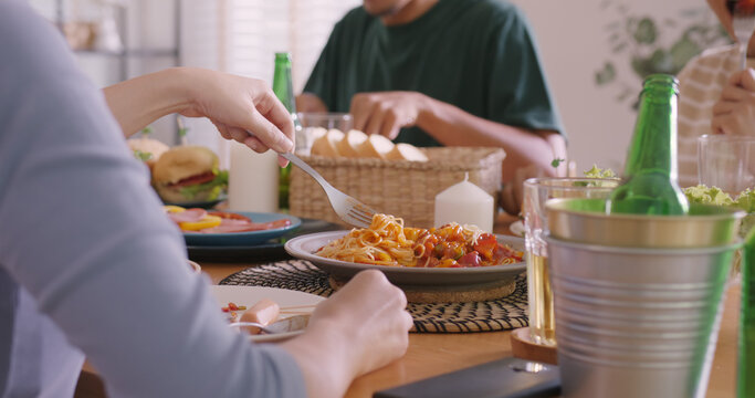 Happy hour good warm summer time diner indoor home. Group of asia people young adult friend man and woman sit at dining table joy fun talk or eat food and drink beer alcohol bottle glass inside house.