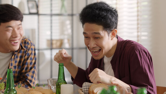 Happy hour good warm summer time diner indoor home. Group of asia people young adult friend man and woman sit at dining table joy fun talk or eat food and drink beer alcohol bottle glass inside house.