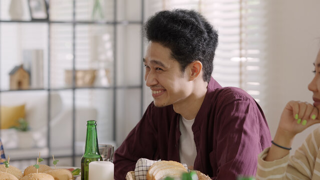 Happy hour good warm summer time diner indoor home. Group of asia people young adult friend man and woman sit at dining table joy fun talk or eat food and drink beer alcohol bottle glass inside house.