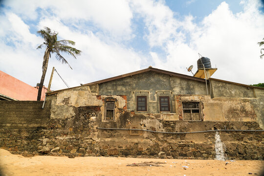 View of an old weathered building with stone walls and a palm tree under a cloudy sky in Galle, Southern Province, Sri Lanka.