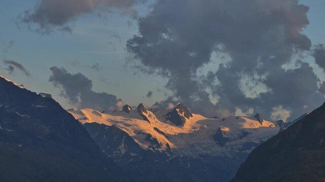 Beautiful Aerial View over Snow Glacier on Mountain Peak in Sunset with Clouds in the Swiss Alps in St Moritz, Maloja, Grisons, Switzerland. (Time Lapse)