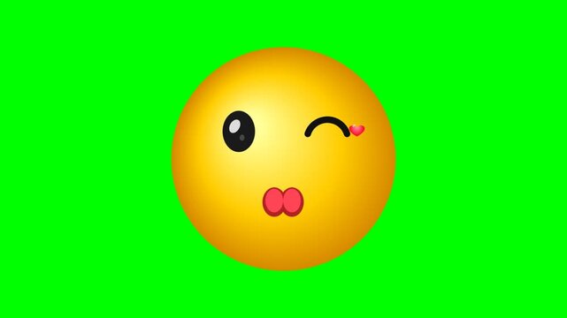 A bright yellow winking emoji face with puckered lips isolated on a green background