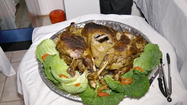 Whole roasted chicken presented on a silver platter with savoy cabbage and tomato garnish, prepared for a professional catering event.
