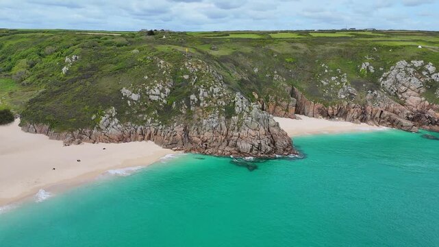 Cinematic aerial video of Porthcurno Beach in Cornwall, England featuring crystal-clear sea, rugged cliffs and stunning coastal scenery.