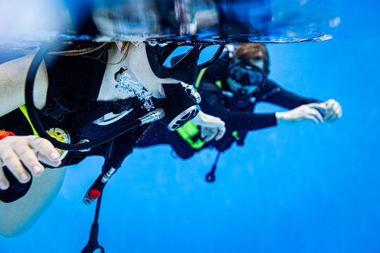 Close-up underwater view of a student and instructor scuba diving in a swimming pool during a training lesson
