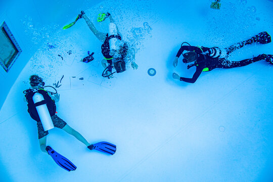 Underwater view of a scuba diving instructor and students assembling a puzzle on the pool floor