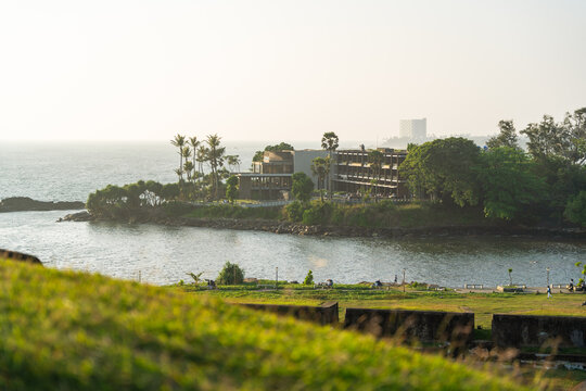 View of a modern coastal resort nestled among palm trees on a peninsula overlooking the Indian Ocean from the historic ramparts Galle, Southern Province, Sri Lanka.