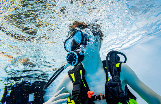 Close-up underwater view of a young boy scuba diving surrounded by a cloud of air bubbles