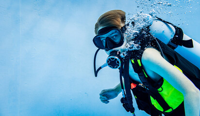 Underwater side view of a young boy scuba diving in a clear blue swimming pool © leszekglasner